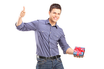 Young man holding a present and giving thumb up