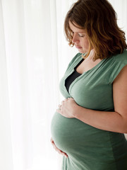 Pregnant young woman looking at her belly