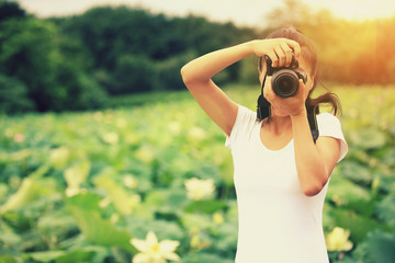 young woman photographer taking photo of blooming lotus at park 