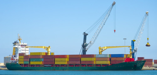 Crane loading containers on a ship in a harbor industrial