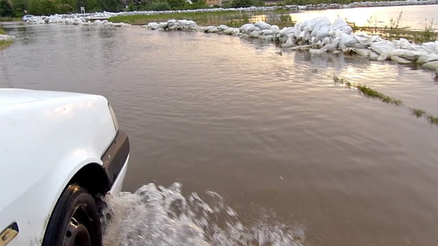 Flooded road, roadside levee of sandbags, slow motion