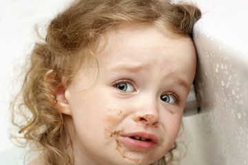 Frightened little smudged toddler in the bath
