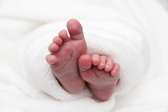 nakte Füße vom Baby eingewickelt in weiße Decke