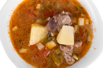 Goulash soup in a yellow bowl on white background
