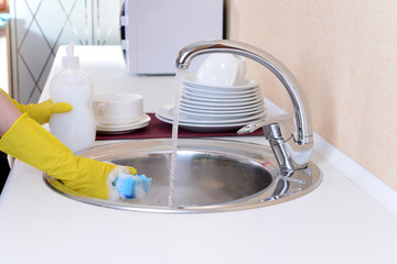 Close up hands of woman washing dishes in kitchen