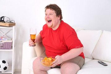 Lazy overweight male sitting on couch and watching television