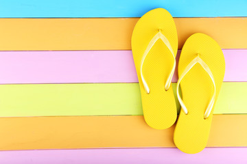 Bright flip-flops on color wooden background