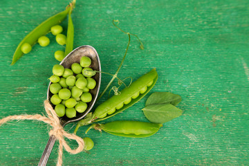 Fresh green peas in spoon on wooden table