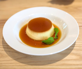 Delicious pudding with caramel and mint leaves. On a white backg