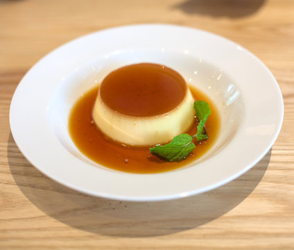 Delicious pudding with caramel and mint leaves. On a white backg