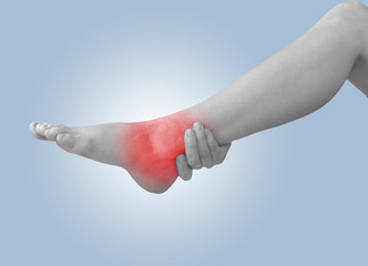 Acute pain in ankle. Woman holding hand to spot of ankle-aches.