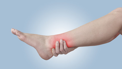 Acute pain in ankle. Woman holding hand to spot of ankle-aches.
