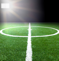 Green soccer field, bright spotlights, illuminated stadium