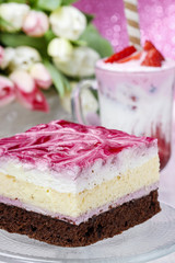 Layer cake with pink icing. Cup of strawberry milkshake