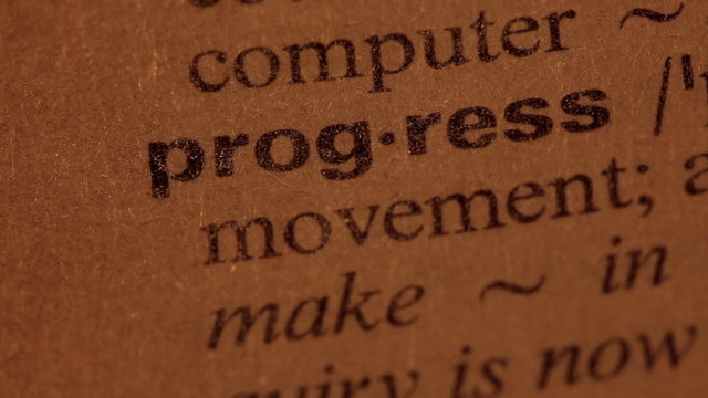 Word Progress in a dictionary. Lit with a spotlight. Three simil