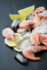 Close-up of raw frozen shrimps on ice cubes, vertical shot