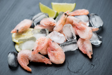 Raw frozen shrimps on ice cubes, horizontal shot, close-up