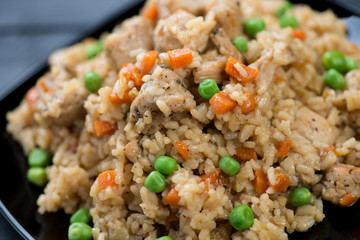 Close-up of pilaf with chicken, carrot and peas, studio shot