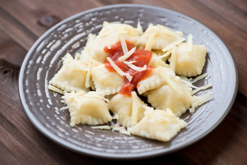 Italian ravioli with tomato sauce and parmesan on a glass plate