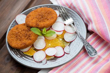Roasted salmon burgers with oranges and radish on a glass plate