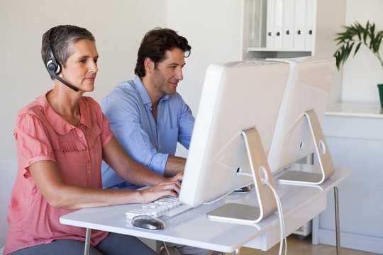 Casual business team working at desk using computers with woman