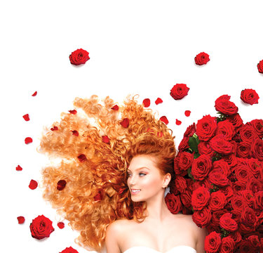 Beauty model girl with curly red hair and beautiful red roses
