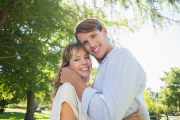 Fototapeta premium Cute couple hugging and smiling at camera in the park