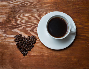 Heart shape made from coffee beans with a cup of coffee