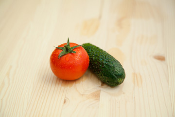 Red tomato and cucumber on a wooden desk