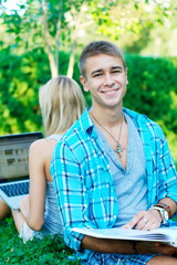 Happy young man with a book with a student on the background