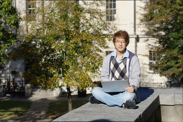Asian student outdoors with laptop