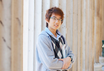 Smiling asian student holding books outdoors