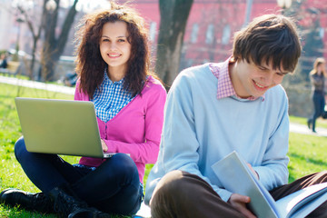 Smiling girl with a laptop with a student at the foreground