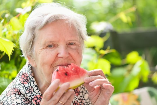 Senior woman smiling and dreaming in garden.