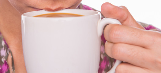 An adult woman sipping coffee with creamer