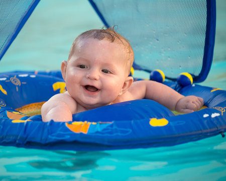 Happy Infant Playing In Pool While Sitting In Baby Float 