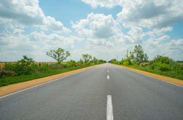 asphalt road. View of rural road and blue cloudy sky