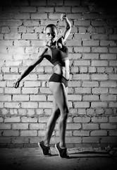 Muscular woman on brick wall (monochrome version)