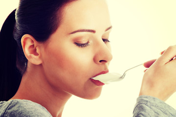 Young casual woman eating a yoghurt.