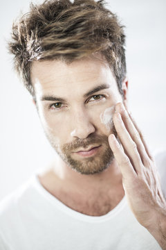 closeup on man applying cream on his face
