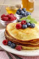 Stack of pancakes with syrup, raspberries and blueberries