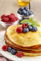 Stack of pancakes with syrup, raspberries and blueberries