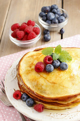 Stack of pancakes with syrup, raspberries and blueberries