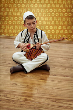 Sitzender Junge spielt Saiteninstrument