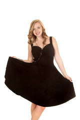 Naklejka premium woman hold out skirt of black dress smiling