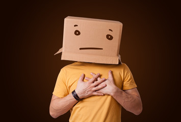 Young man gesturing with a cardboard box on his head with straig