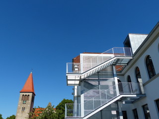 Außentreppe an der Grundschule mit Kirchturm der evangelischen Kirche vor blauem Himmel im...