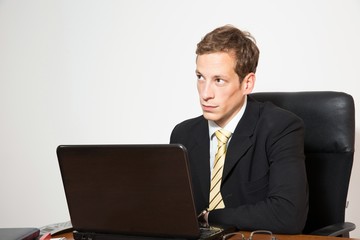 Young business dressed male working on laptop.