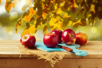 Apples on wooden table over autumn bokeh background