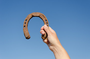 hand hold vintage horseshoe on blue sky background